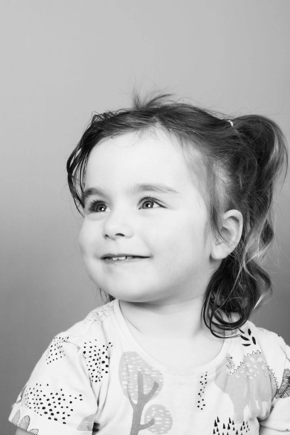 Black and white portrait of a little girl with pigtails glancing sideways