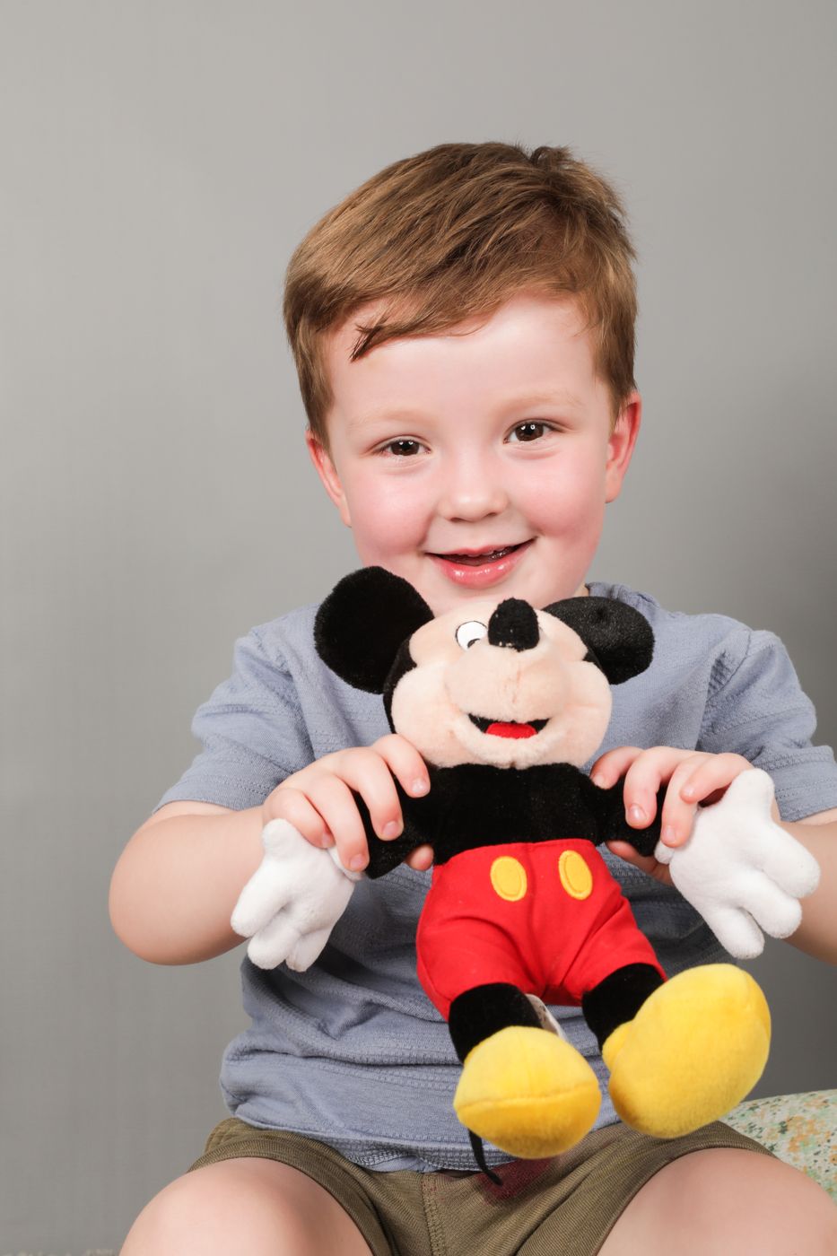 A smiling boy holding up his favourite soft toy