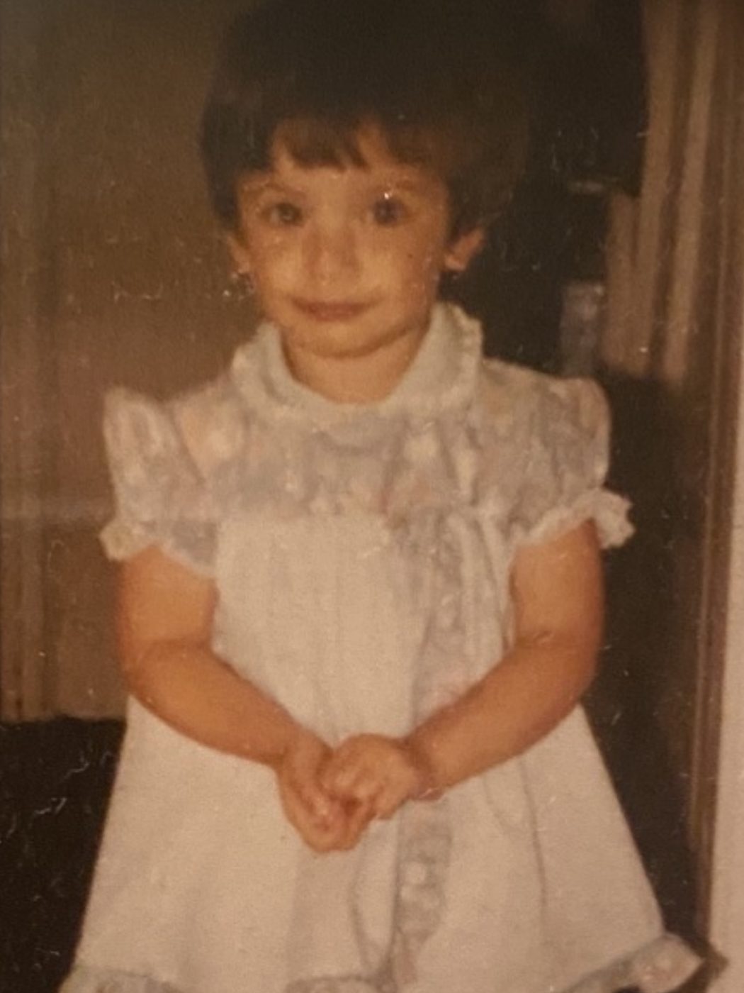 Marianne as a toddler in a white frilled dress